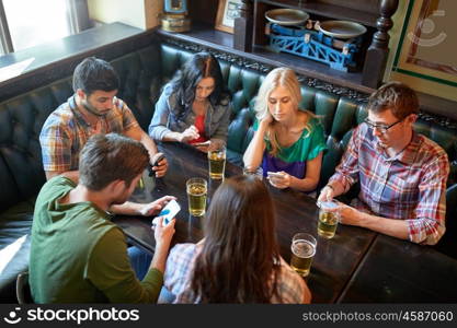 people, leisure, friendship and communication concept - friends with smartphones drinking beer and texting at bar or pub