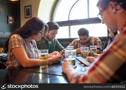 people, leisure, friendship and communication concept - friends with smartphones drinking beer and texting at bar or pub