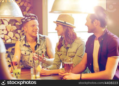 people, leisure, friendship and communication concept - group of happy smiling friends drinking beer and cocktails at bar or pub