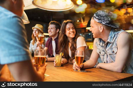 people, leisure, friendship and communication concept - group of happy smiling friends drinking beer and cocktails talking at bar or pub