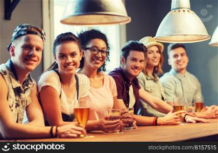 people, leisure, friendship and communication concept - group of happy smiling friends drinking beer, water or cocktails at bar or pub