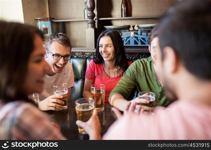 people, leisure, friendship and communication concept - happy friends drinking beer and talking at bar or pub