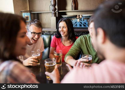 people, leisure, friendship and communication concept - happy friends drinking beer and talking at bar or pub