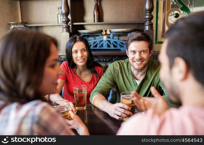 people, leisure, friendship and communication concept - happy friends drinking beer and talking at bar or pub