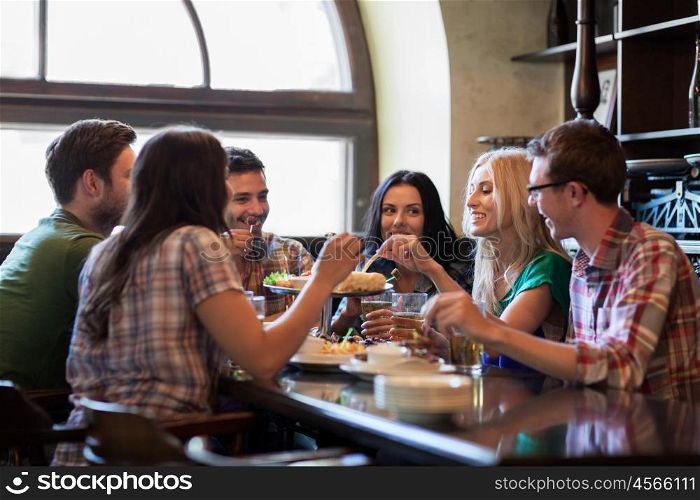 people, leisure, friendship and communication concept - happy friends drinking beer and eating snacks at bar or pub