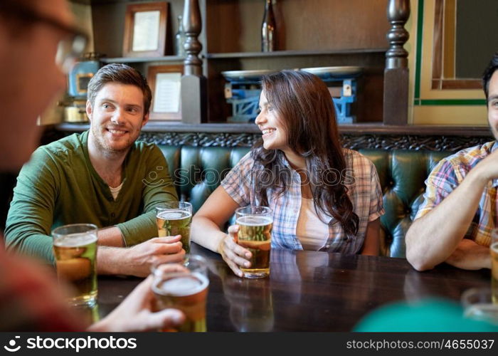 people, leisure, friendship and communication concept - happy friends drinking beer and talking at bar or pub