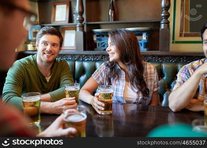 people, leisure, friendship and communication concept - happy friends drinking beer and talking at bar or pub