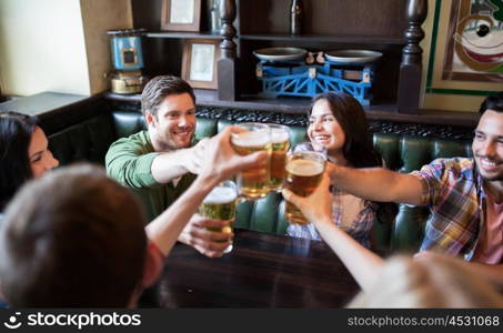 people, leisure, friendship and communication concept - happy friends drinking beer, talking and clinking glasses at bar or pub