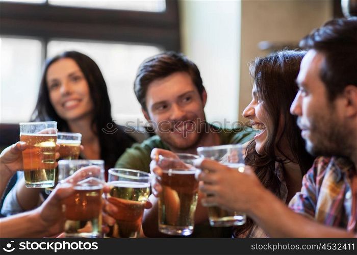people, leisure, friendship and communication concept - happy friends drinking beer, talking and clinking glasses at bar or pub