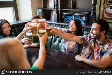 people, leisure, friendship and communication concept - happy friends drinking beer, talking and clinking glasses at bar or pub