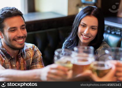 people, leisure, friendship and communication concept - happy friends drinking beer, talking and clinking glasses at bar or pub