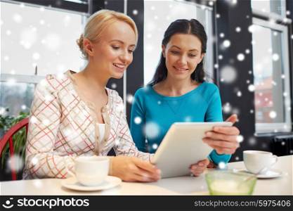 people, leisure, friendship and communication concept - happy young women meeting and drinking tea or coffee at cafe over snow effect