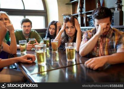 people, leisure, friendship and entertainment concept - friends drinking beer and watching sport game or football match at bar or pub