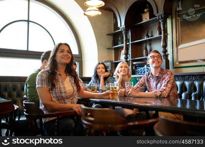 people, leisure, friendship and entertainment concept - happy friends drinking beer and watching sport game or football match at bar or pub