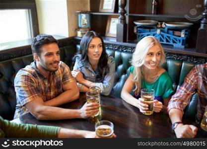 people, leisure, friendship and entertainment concept - happy friends drinking beer and watching sport game or football match at bar or pub. friends with beer watching football at bar or pub