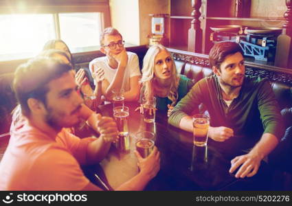 people, leisure, friendship and entertainment concept - happy friends drinking beer and watching sport game or football match at bar or pub. friends with beer watching football at bar or pub