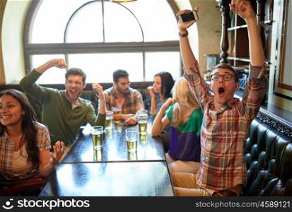 people, leisure, friendship and entertainment concept - happy friends drinking beer, watching sport game or football match and celebrating victory at bar or pub