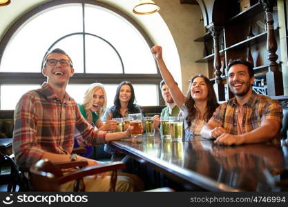 people, leisure, friendship and entertainment concept - happy friends drinking beer, watching sport game or football match and celebrating victory at bar or pub