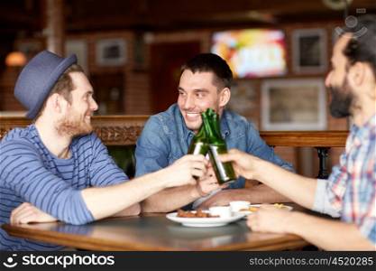people, leisure, friendship and party concept - happy male friends drinking bottled beer at bar or pub and clinking bottles
