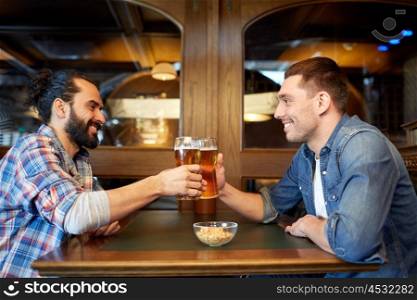 people, leisure, friendship and party concept - happy male friends drinking draft beer at bar or pub and clinking glasses