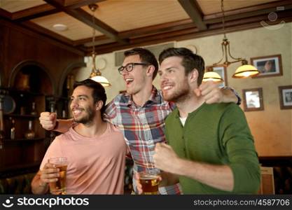 people, leisure, friendship and sport concept - happy male friends or fans watching sport game or football match and drinking beer at bar or pub