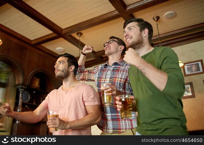 people, leisure, friendship and sport concept - happy male friends or fans watching sport game or football match and drinking beer at bar or pub