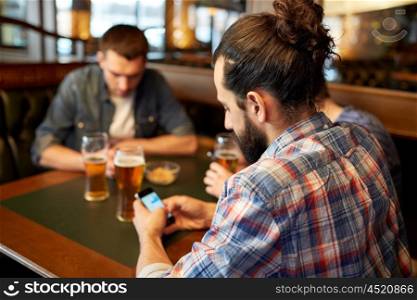 people, leisure, friendship and technology concept - close up of male friends with smartphones drinking beer at bar or pub