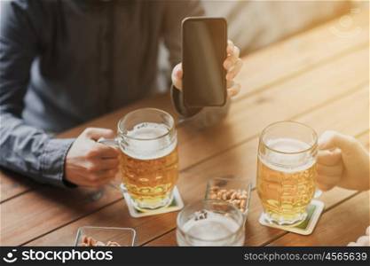 people, leisure, friendship and technology concept - close up of two male friends drinking beer with snacks and showing smartphone black blank screen at bar or pub