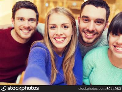 people, leisure, friendship and technology concept - group of smiling friends taking selfie