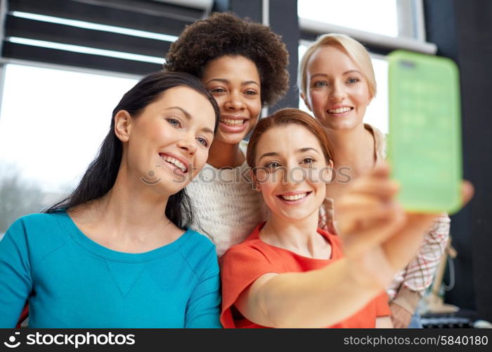 people, leisure, friendship and technology concept - happy young women taking selfie with smartphone