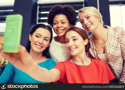 people, leisure, friendship and technology concept - happy young women taking selfie with smartphone