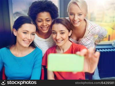 people, leisure, friendship and technology concept - happy young women taking selfie with smartphone. happy young women taking selfie with smartphone