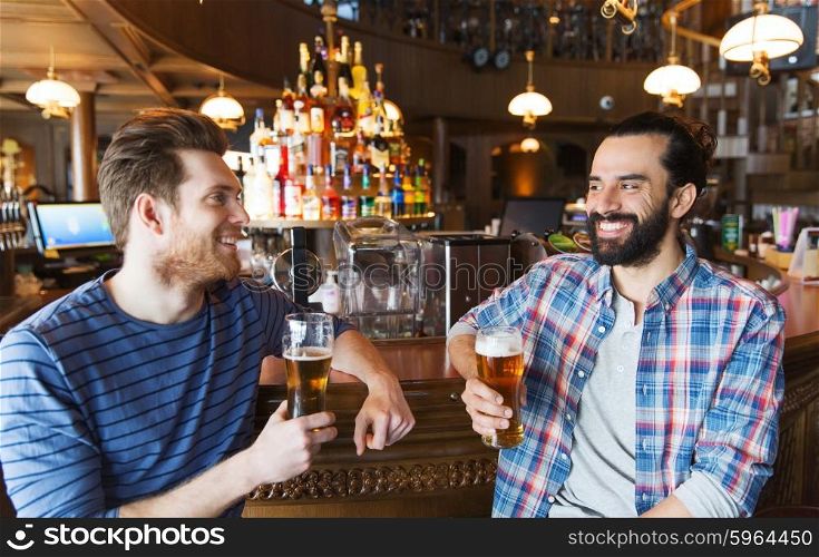people, leisure, friendship, communication and bachelor party concept - happy male friends drinking beer and talking at bar or pub