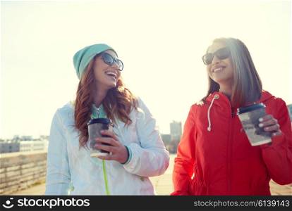 people, leisure, friendship, communication and takeaway drinks concept - happy teenage girls with coffee cups on city street