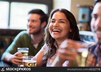 people, leisure, friendship, emotion and communication concept - happy woman with her friends drinking beer at bar or pub and laughing