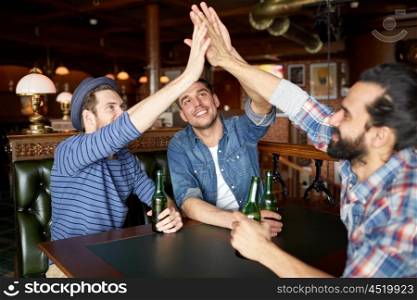 people, leisure, friendship, gesture and bachelor party concept - happy male friends drinking bottled beer and making high five at bar or pub