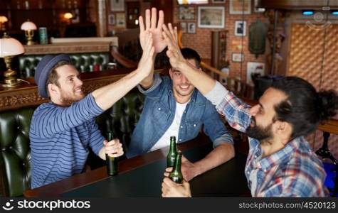 people, leisure, friendship, gesture and bachelor party concept - happy male friends drinking bottled beer and making high five at bar or pub