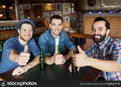 people, leisure, friendship, gesture and bachelor party concept - happy male friends drinking bottled beer and showing thumbs up at bar or pub