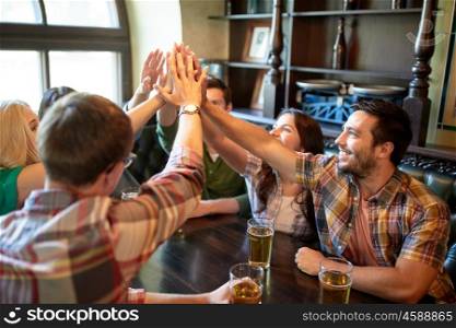 people, leisure, friendship, gesture and communication concept - happy friends drinking beer and making high five at bar or pub
