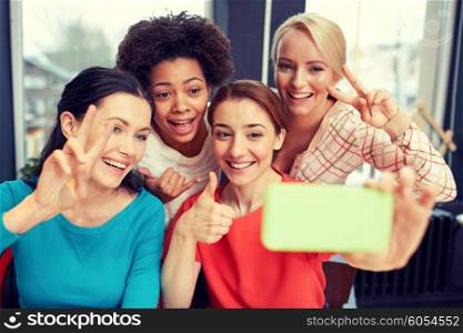 people, leisure, friendship, gesture and technology concept - happy young women taking selfie with smartphone and showing victory gesture