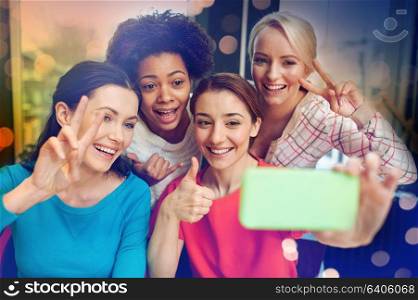 people, leisure, friendship, gesture and technology concept - happy young women taking selfie with smartphone and showing victory gesture. happy young women taking selfie with smartphone
