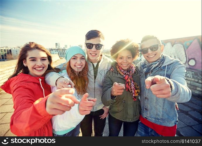 people, leisure, gesture and teenage concept - group of happy teenage friends pointing fingers at you on city street