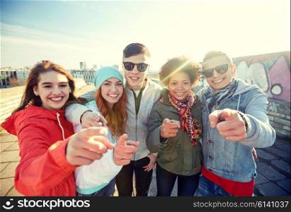 people, leisure, gesture and teenage concept - group of happy teenage friends pointing fingers at you on city street