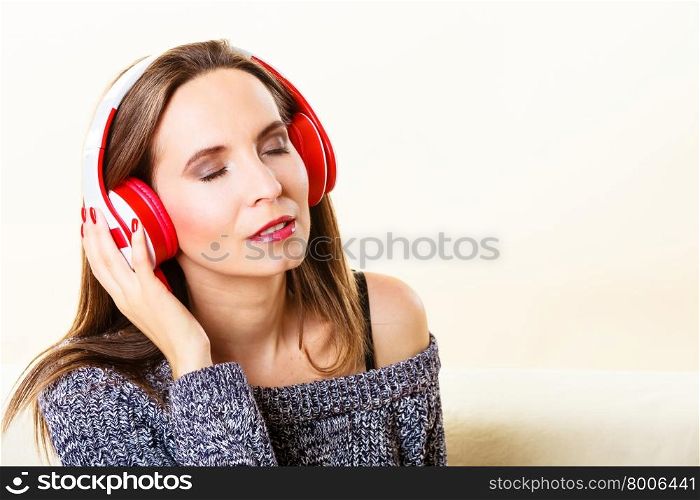 People leisure relax concept. Woman casual style red big headphones listening music mp3, sitting on couch at home relaxing
