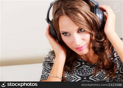 People leisure relax concept. Young woman in big headphones listening music mp3 relaxing at home