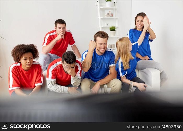 people, leisure, rivalry and sport concept - happy and sad friends or football fans watching soccer game or match at home