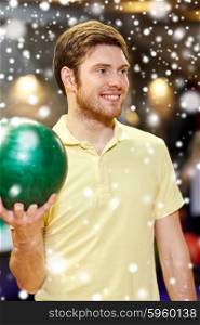 people, leisure, sport and entertainment concept - happy young man holding ball in bowling club at winter season