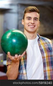 people, leisure, sport and entertainment concept - happy young man holding ball in bowling club