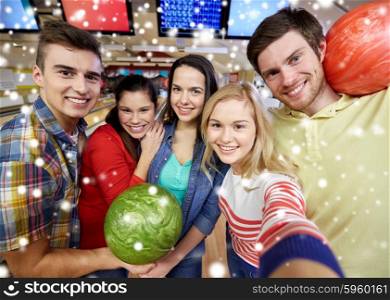 people, leisure, sport, friendship and entertainment concept - happy friends taking selfie with camera or smartphone in bowling club at winter season