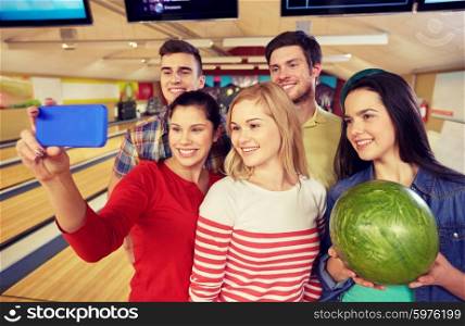 people, leisure, sport, friendship and entertainment concept - happy friends taking selfie with smartphone in bowling club